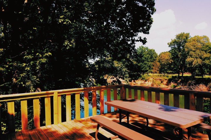 a wooden park bench sitting in front of a fence